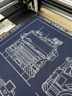 Close-up of pen plotter drawing a fire engine technical illustration in white ink on dark blue paper