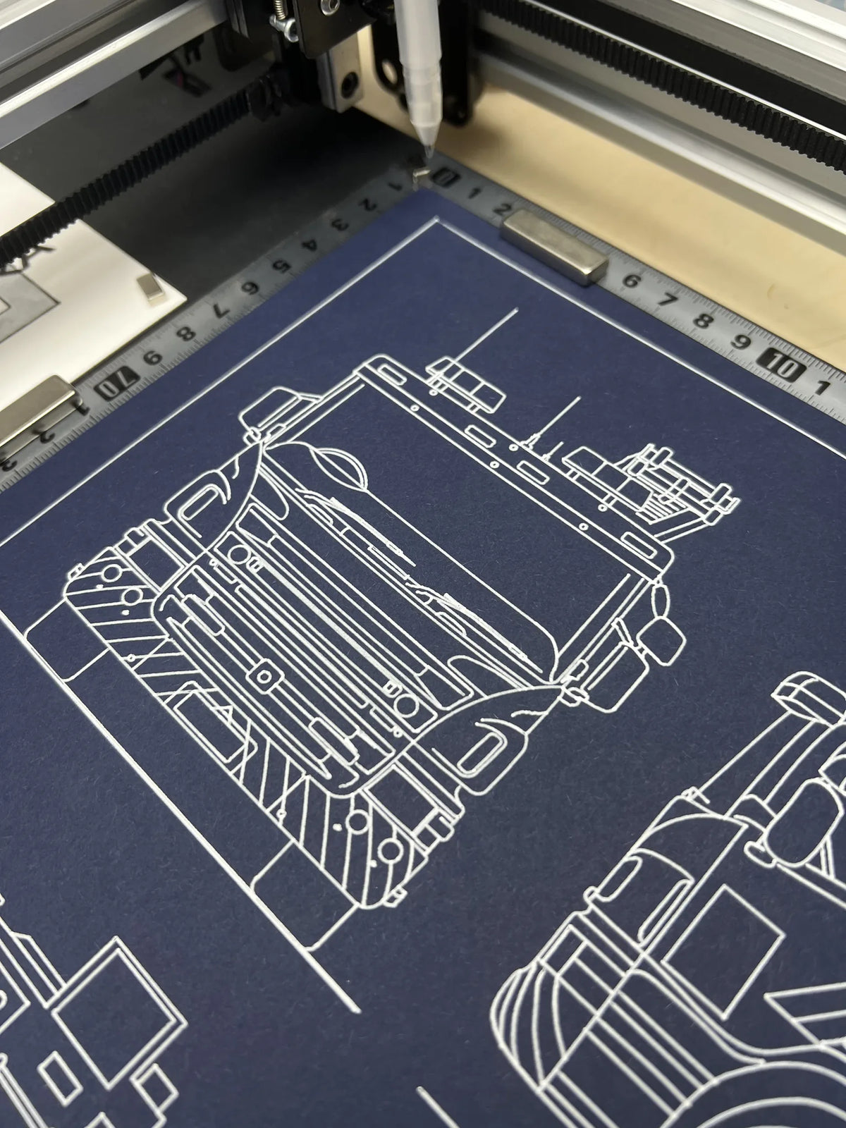 Close-up of pen plotter drawing a fire engine technical illustration in white ink on dark blue paper
