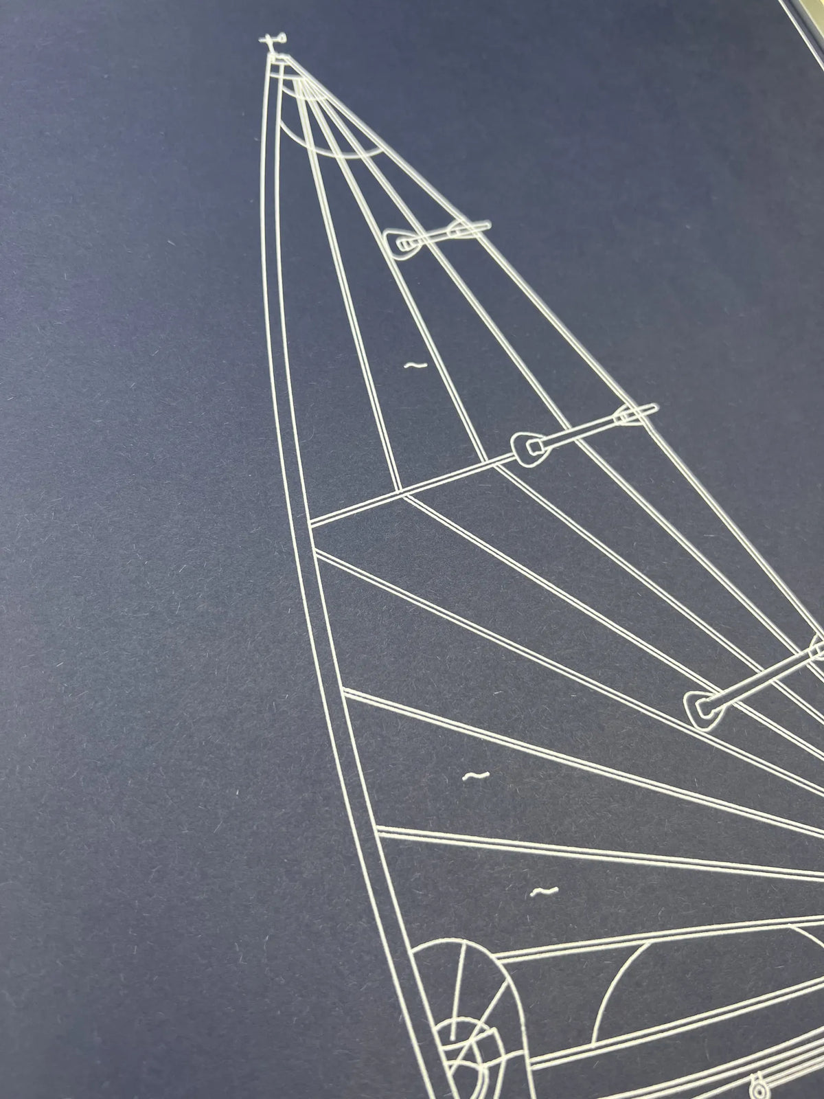 A close-up of a dark navy blue print or surface featuring a white line drawing of a sailboat rigging diagram.