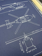 Close-up of Eurocopter EC135 helicopter blueprint with dimensions, white ink line drawing on navy paper