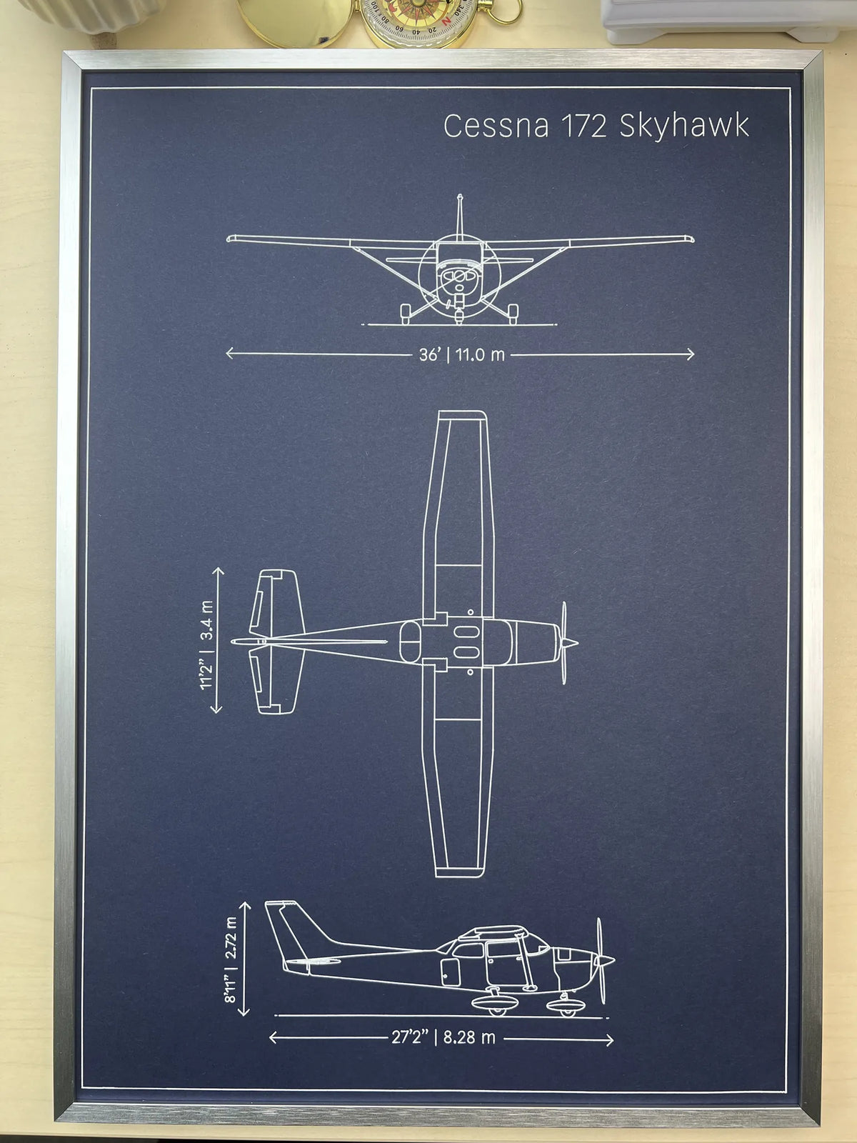 Framed Cessna 172 Skyhawk blueprint in silver metal frame, three-view aircraft drawing with dimensions
